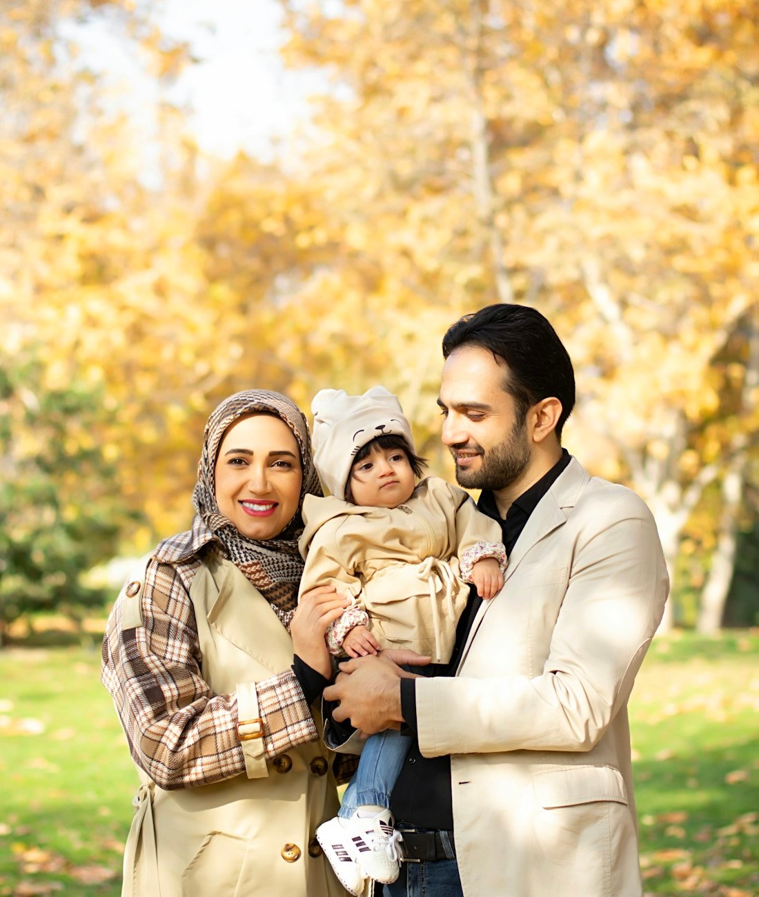 Smiling family: mother in hijab, father and their baby outdoors