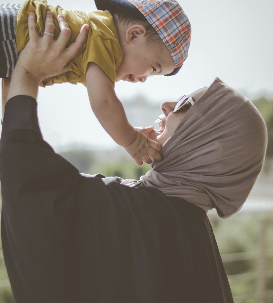 Mother in hijab lifting her young son
